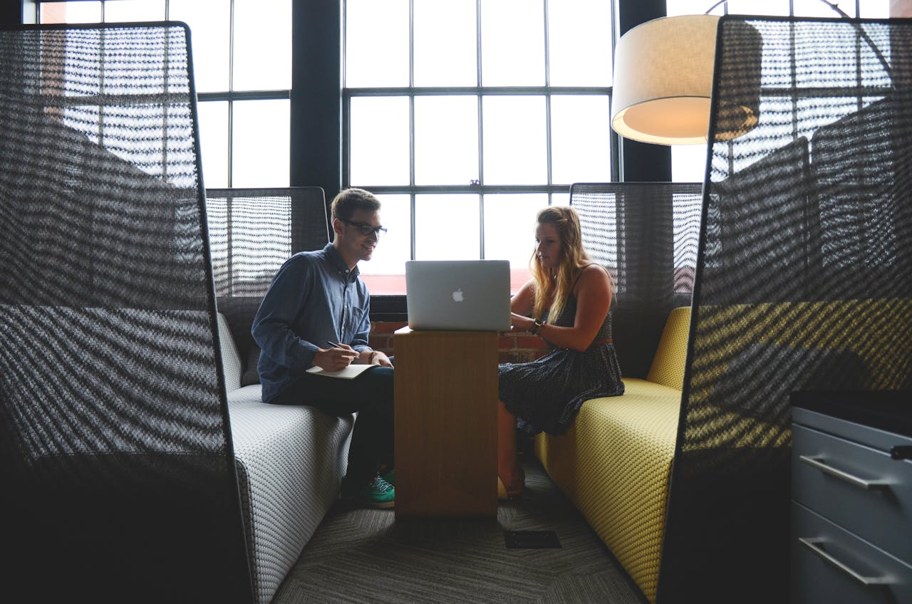 who-we-are Two adults discussing work and collaborating in a modern office lounge area.